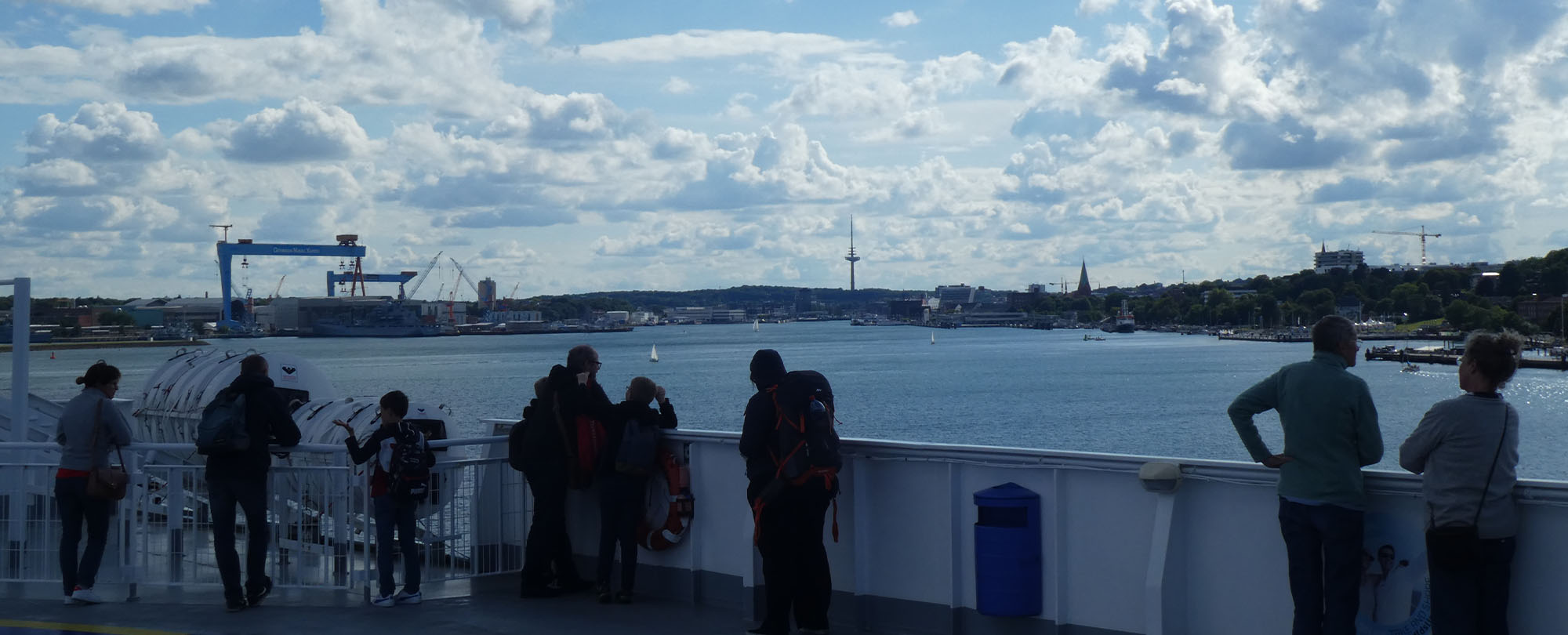 Personen auf Schiff mit Hafen im Hintergrund