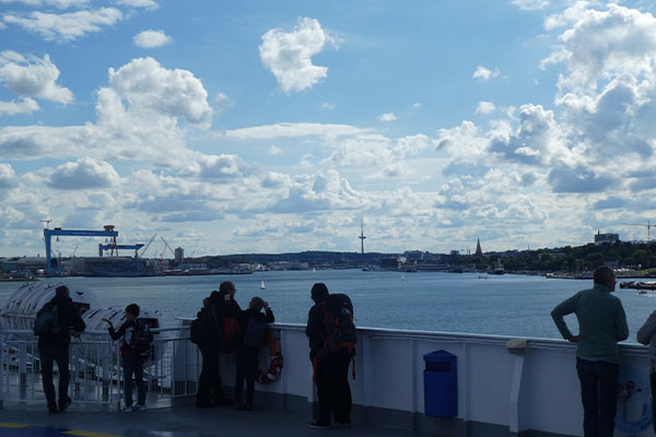 Personen auf Schiff mit Hafen im Hintergrund