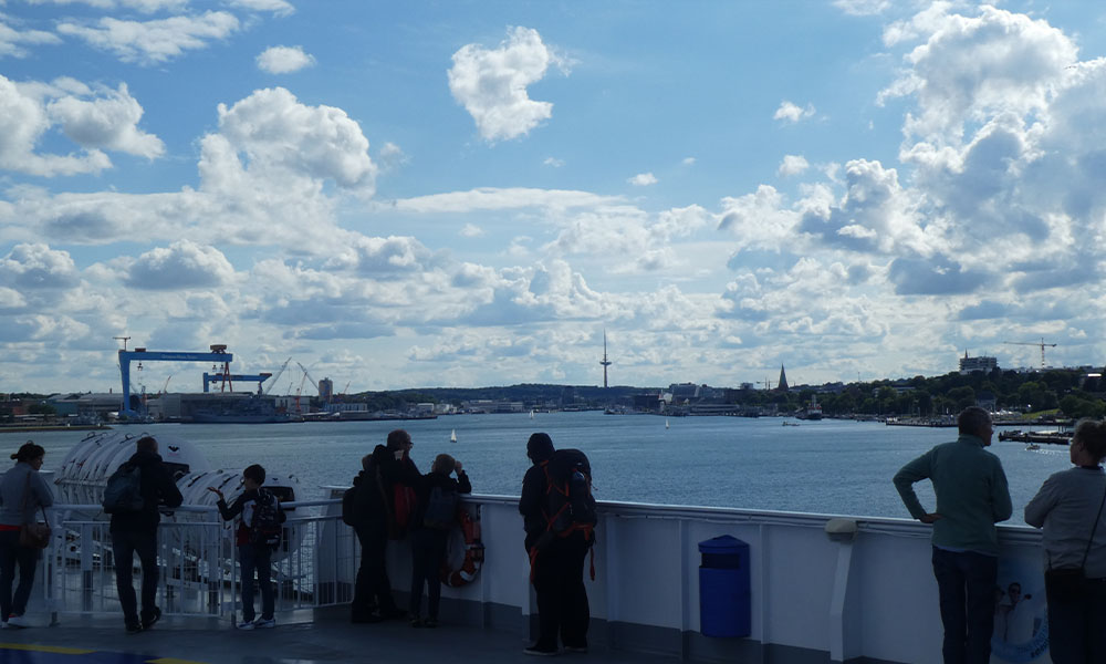 Personen auf Schiff mit Hafen im Hintergrund